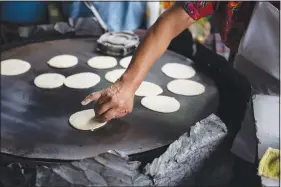 ?? ?? Felipa de Jesus Otzoy, 55, flips corn tortillas cooking on a hot comal Oct. 16 at her market stall in Guatemala City. Otzoy has been making the handmade tortillas in the same place for 35 years.