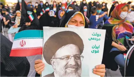  ?? ATTA KENARE AFP VIA GETTY IMAGES ?? A woman holds a poster of Iran’s newly elected president Ebrahim Raisi, with text in Persian reading “government of the people, strong Iran,” as supporters celebrate his victory in Imam Hussein square in Tehran, Iran, on Saturday.