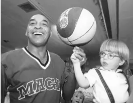  ?? EILEEN MARIE GARCIA ?? Codey Fears, a 2-year-old cancer patient, learns to spin a basketball from former Harlem Globetrott­er Curly Neal during a barbecue fundraiser to help the Fears family.