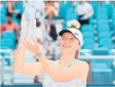  ?? MICHAEL REAVES/GETTY ?? Iga Swiatek raises the Butch Buchholz Trophy after defeating Naomi Osaka in the singles final Saturday in Miami Gardens, Florida.