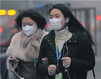  ?? FOTO: AFP ?? Menschen in Sorge: Zwei Frauen gehen mit Atemschutz­masken durch das vernebelte Peking.