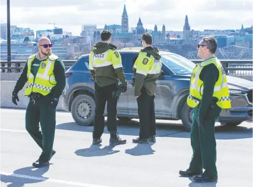  ?? Wayne Cuddington / Postmedia news ?? Quebec Provincial Police checking for drivers and passengers possibly infected with COVID-19 stop vehicles on the
Macdonald- Cartier Interprovi­ncial Bridge on Wednesday as they entered Gatineau from Ottawa.