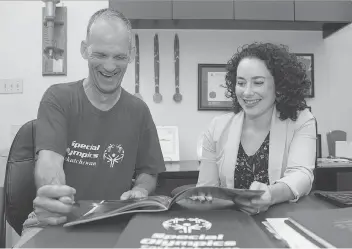  ?? TROY FLEECE ?? Robbie Bomber, a Special Olympics athlete, and Faye Matt, CEO of Special Olympics Saskatchew­an, look over part of the bid for Regina to host the 2020 Special Olympics Canada Winter Games.