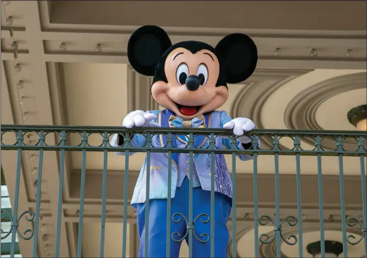  ?? TED SHAFFREY / ASSOCIATED PRESS FILE (2022) ?? An actor dressed as Mickey Mouse greets visitors at the entrance to Magic Kingdom Park at Walt Disney World Resort in Lake Buena Vista, Fla. Winnie-the-pooh and Mickey Mouse have recently entered the public domain, making it possible for artists to use them freely.