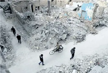  ?? ABD DOUMANY/GETTY IMAGES ?? Syrians walk past the rubble of destroyed buildings in the rebel-held town of Douma, on the eastern outskirts of the capital Damascus, on Monday. Government documents obtained by the National Post reveal why Canada rejected dozens of Syrians as...