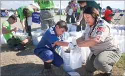  ??  ?? Cub scout Christophe­r Plumlee, 8, pours sand into a luminary paper bag with his mother Gladis, right, Saturday, Oct. 6 at the 20th annual Relay For Life at Summit Charter Collegiate Academy in Portervill­e. Scouts from Troop 132 and Pack 3116 prepare over 1,000 bags for the event.