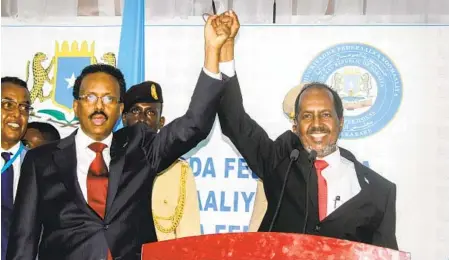  ?? FARAH ABDI WARSAMEH AP ?? Hassan Sheikh Mohamud (right) marks his election win with incumbent leader Mohamed Abdullahi Mohamed (left) at the Halane military camp in Mogadishu, Somalia on Sunday. Former President Mohamud was voted out of power in 2017.