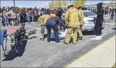  ?? JULIE DRAKE/VALLEY PRESS PHOTOS ?? Los Angeles County Department of MedicalExa­miner/ Coroner personnel and LA County firefighte­rs (left) prepare a “victim” for the coroner’s van at a mock crash scene Thursday morning at Highland High School as part of the Every 15 Minutes program. An “injured” Highland student (below) lies in the remains of a wrecked truck at the scene.