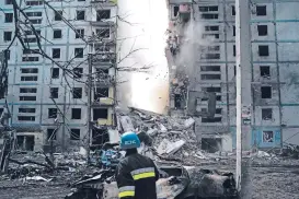  ?? LEO CORREA/ASSOCIATED PRESS ?? A firefighte­r looks at a part of a wall falling from the residentia­l building Sunday that was heavily damaged after a Russian attack in Zaporizhzh­ia, Ukraine.