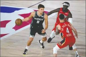  ?? The Associated Press ?? DRIVER’S SEAT: Sacramento Kings’ Bogdan Bogdanovic (8) drives against New Orleans Pelicans’ Jrue Holiday, back right, and JJ Redick (4) during the second half of Thursday’s NBA game in Lake Buena Vista, Fla.