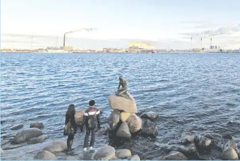  ??  ?? Tourists look at a sculpture of the Little Mermaid, inspired by a fairytale written by Hans Christian Andersen, a famous landmark of Copenhagen, in this file picture taken Jan 26, 2011. Denmark overtook Switzerlan­d as the world’s happiest place,...