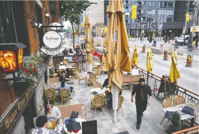  ?? COLE BURSTON / BLOOMBERG ?? Diners sit at a restaurant patio in Toronto after the open-air spaces were allowed to open last week.