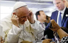  ?? ANDREW MEDICHINI / AP ?? Pope Francis listens to a recorded message offered by a journalist during his flight to Bogota, Colombia, on Wednesday. In addition to Bogota, the pope will visit Villavicen­cio, Medellin and Cartagena during his five-day apostolic trip.