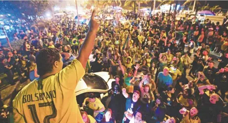  ??  ?? Partidario­s del candidato brasileño Jair Bolsonaro celebran afuera de su casa en Río de Janeiro, tras el resultado de las elecciones generales.