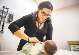  ?? Amr Alfiky / Associated Press ?? Dr. Jasmine Saavedra, a pediatrici­an at Esperanza Health Centers whose parents emigrated from Mexico, examines a newborn baby, Alondra Marquez, in her Chicago clinic Tuesday.