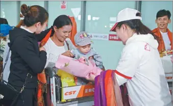  ?? ZHAI JIAN / FOR CHINA DAILY ?? Volunteers present flowers and shawls to a mother and her child at Kunming Changshui Internatio­nal Airport in Kunming, Yunnan province, on Wednesday. Ten children from Myanmar with congenital heart disease have come to China to receive free treatment thanks to a campaign by the China Charity Federation and local hospitals. Twelve children received treatment last year, while another five will receive treatment in Kunming soon.