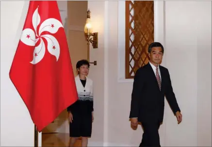  ?? REUTERS ?? Hong Kong Chief Executive Leung Chun-ying (right) and Chief Secretary Carrie Lam walk past a Hong Kong flag as they attend a news conference in Hong Kong on Thursday.