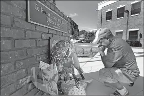  ?? AP/Orlando Sentinel/RED HUBER ?? After placing flowers at a makeshift memorial Saturday, Miguel Velez prays for the officer killed in Kissimmee, Fla.