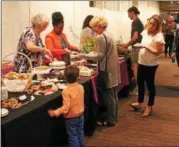  ??  ?? Event-goers visit the dessert table at Capital Roots’ 31st annual Spring Brunch, held Sunday at the Empire State Plaza Convention Hall in Albany.