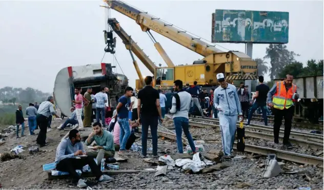  ?? Associated Press ?? ↑
People break their fast at the site of a passenger train that derailed near Banha, Qalyubia province, on Sunday.