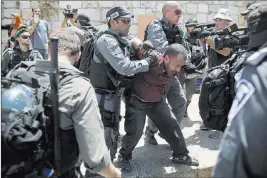 ?? Oded Balilty ?? The Associated Press Israeli police officers detain a Palestinia­n man Wednesday outside the Lion’s Gate in Jerusalem’s Old City.