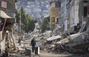  ?? (AP/Unal Cam) ?? A man walks past destroyed buildings Tuesday in Antakya, southeaste­rn Turkey. More photos at arkansason­line.com/222quake/.