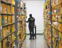  ?? BEBETO MATTHEWS / AP FILE (2016) ?? An employee of Amazon Primenow stocks shelves at a distributi­on hub in New York. Amazon announced Oct. 2 that it would raise its hourly minimum wage to $15, but employees will also lose two benefits they relied on: monthly bonuses that could top hundreds of dollars and a chance to own Amazon stock.