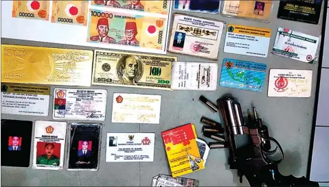  ?? CHUSNUL CAHYADI/JAWA POS ?? ASLI ATAU PALSU?: Barang bukti yang sempat diamankan dari tiga orang yang diduga intel gadungan. Di antaranya, kartu identitas, beberapa lembar pecahan lama uang seratus ribu rupiah, cetakan uang dolar Amerika Serikat, dan airsoft gun. Polisi melepas ketiganya dengan alasan tidak ada laporan warga tentang penipuan.