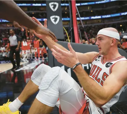  ?? CHICAGO TRIBUNE JOHN J. KIM/ ?? Bulls guard Alex Caruso is helped off the floor after taking a foul in the second quarter against the Nuggets on Oct. 7 at the United Center.