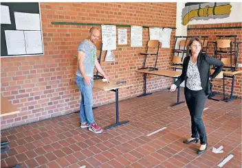  ?? FOTO: WOLFGANG KAISER ?? Elke Terbeck und Lehrer Eric Bongartz messen den Tischabsta­nd in einer der Schulklass­en am Rhein-Maas-Berufskoll­eg.