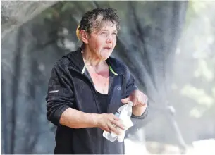  ?? (Jason Redmond/Reuters) ?? KATHERINE MILTON, originally from Juneau, Alaska, enjoys a homemade cooling-off mist station that a family set up in their front yard especially for homeless people during the scorching weather in Seattle.