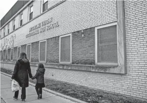  ?? CAMILLE C. FINE FOR USA TODAY ?? Pedestrian­s walk by Vaughn High School in Chicago, the first school in the Chicago Public Schools to close.