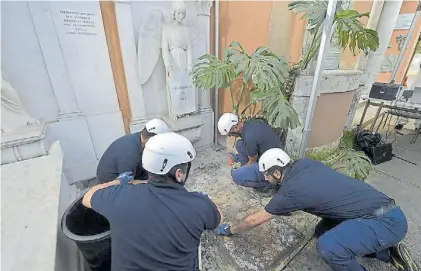  ?? AFP ?? Búsqueda. Un grupo de operarios del cementerio teutónico vaticano trata de levantar una lápida.