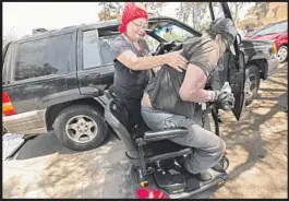  ??  ?? CARLA McCUE helps her husband, Lawrence, onto his wheelchair. Recently, a doctor told Lawrence that his kidneys were functionin­g at 19% of their capacity.