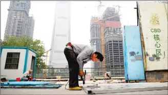  ??  ?? In this file photo, a worker assembles an aluminum platform outside a constructi­on site at the Central Business District of Beijing. China’s economic growth ticked higher to 6.9 percent in the first quarter of the year, according to the latest figures. The official data released on April 17, show that the world’s second-biggest economy grew at a slightly faster pace in the January-March period compared with the previous quarter’s 6.8 percent expansion (AP)