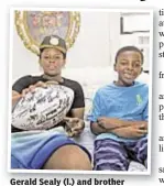  ??  ?? Gerald Sealy (l.) and brother Jarell Cummings show off football signed by entire Raiders team.