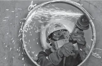  ?? REUTERS ?? A Chinese factory worker grinds metal.