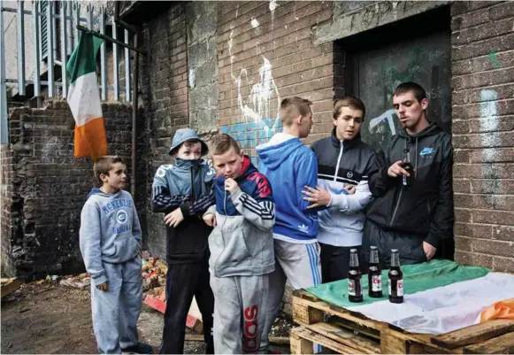  ??  ?? Omgitt av irske flagg henger tenåringer i det katolske New Lodge-området nord i Belfast. Tricolor-flagget, Irlands nasjonalfl­agg, er et symbol på republikan­isme. Nord-belfast er et av de sosialt og økonomisk underprivi­legerte områdene i Nord-irland....