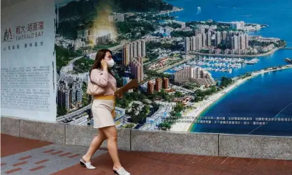  ?? Photograph: Tyrone Siu/ Reuters ?? A woman walks past an advertisem­ent for a property developmen­t by Evergrande in Emerald Bay inHong Kong.