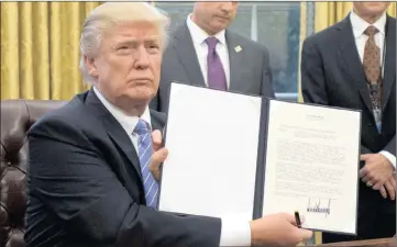  ??  ?? President Donald Trump shows the Executive Order withdrawin­g the US from the Trans-Pacific Partnershi­p after signing it in the Oval Office of the White House in Washington, DC, US, on Monday.