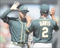  ?? NHAT V. MEYER — STAFF PHOTOGRAPH­ER ?? Stephen Piscotty, left, and Khris Davis high-five after Sunday’s win. The A’s won two of three at AT&amp;T Park and the teams meet in Oakland this weekend.
