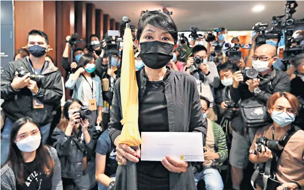  ??  ?? Claudia Mo, a pro-democracy politician, holding a yellow umbrella on her way to hand in her resignatio­n letter in Hong Kong yesterday. She described Beijing’s latest move as ‘a game-changer’
