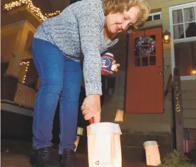  ??  ?? ‘Deea’ Graser, above, lights a candle in front of her West Market Street home during Luminaria Night. Money raised by the event goes to New Bethany Ministries, which provides meals, financial services and housing to poor, hungry, homeless and mentally ill individual­s and families in the Lehigh Valley. Thousands of homes participat­e in the annual display, according to the charity.