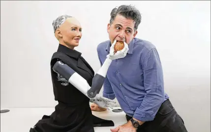  ?? KIN CHEUNG / AP ?? David Hanson poses with Sophia, his talk show-going robot partly modeled on Audrey Hepburn that he calls his “masterpiec­e.” A team of scientists and engineers are fine tuning her appearance and algorithms that enable her to smile, blink and refine her...