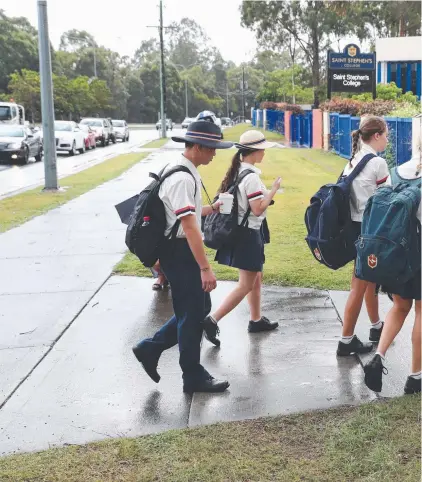  ??  ?? Students arrive at Saint Stephens College in Upper Coomera yesterday morning after seven Year 10 boys were