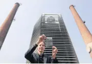  ?? AP ?? Dutch artist Daan Roosegaard­e shows smog particles collected by the Smog Free Tower on display in between chimney stacks as he presents his machine at D-751 art district in Beijing.