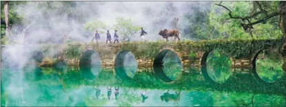  ?? PHOTOS BY YAO XIANDUN AND WU DONG / FOR CHINA DAILY ?? Villagers walk across a stone bridge enveloped by the morning mist in Libo county, Guizhou province.