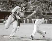  ?? Chris Carlson / Associated Press ?? Angels starter Garrett Richards tags out Marwin Gonzalez after the Astros left fielder tried to reach on a bunt in the fourth inning Tuesday night.