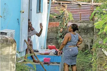  ?? [AP PHOTO] ?? Two local women chat as a Dutch Marine helps out Monday in preparatio­n for the arrival Hurricane Maria, in Oranjestad, Statia, on the Leeward Islands.