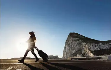  ?? —AP ?? A woman walks on the Spanish side of the border between Spain and the British overseas territory of Gibraltar with the Rock as a background, in La Linea de la Concepcion, Southern Spain.